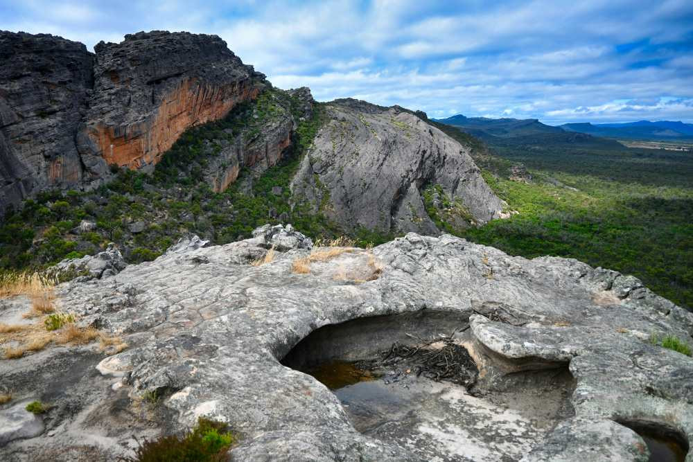 a-view-of-a-rocky-outcropping-with-trees-and-mountains-in-the-background-enguerrand-photography-d9fefrdbih8-unsplash.jpg